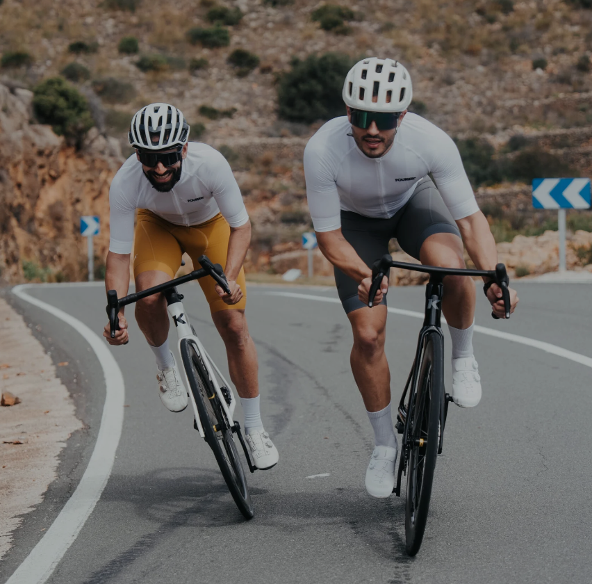 Dos ciclistas de carretera KDNS ascendiendo por una curva de montaña
